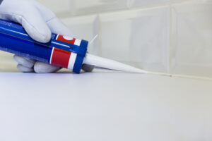 Plumber applying silicone sealant to the countertop and ceramic